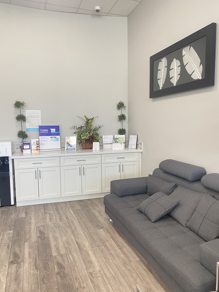 A clean, modern dental treatment room with a mint-green dental chair, cabinetry, and a round wall mirror - Dentist Federal Way WA