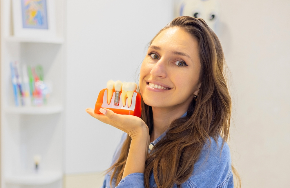dental patient holding a tooth model - dental crowns dental patient holding a tooth model - dental crowns